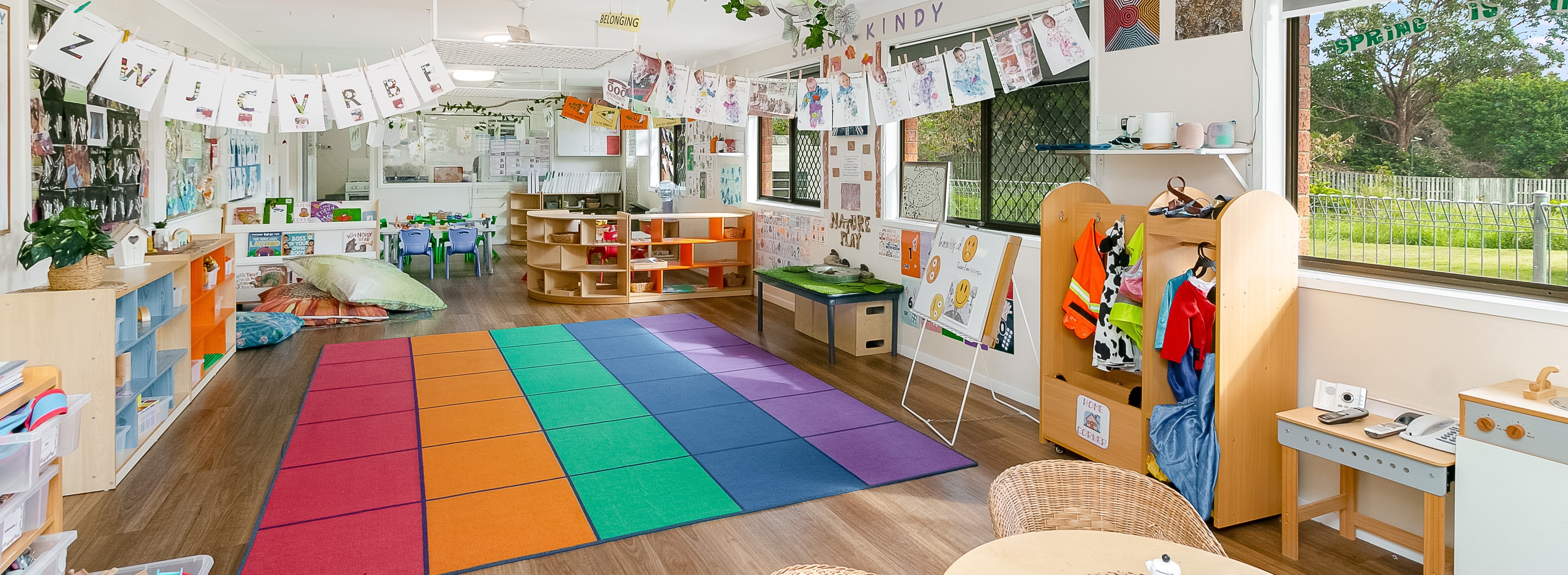 a colorful senior kindy classroom with a rainbow rug in Tiny Tots Early Learning Centre