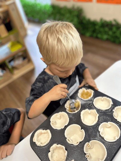 a boy pours a filling on a small pie