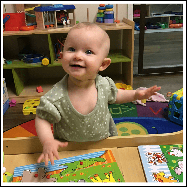 a happy toddler wearing a green dress playing in the babies room