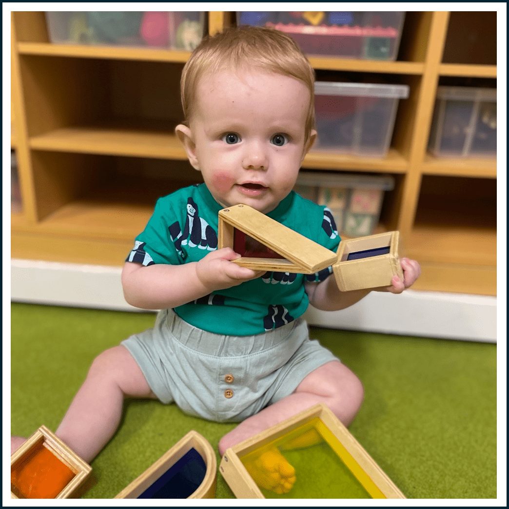 a baby boy wearing a green shirt holding a wooden shape toy